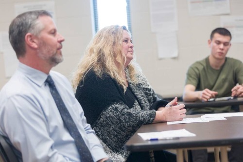 Adults seated at tables in a classroom setting during a group discussion