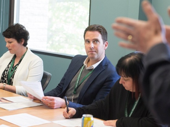 People seated at a table review documents during a meeting in a bright conference room.