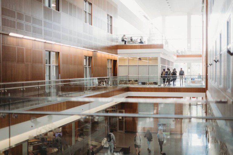 Bright interior of a university health sciences building with students walking between levels.