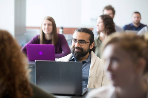 Students seated in a classroom using laptops during a lecture or group session