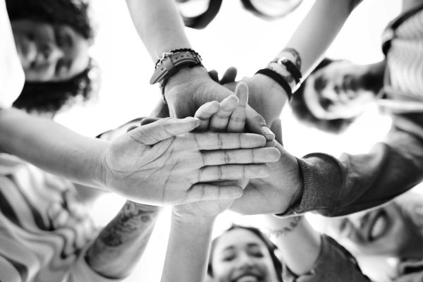 worms eye view of group of teenagers in a circle with their hands on top of another