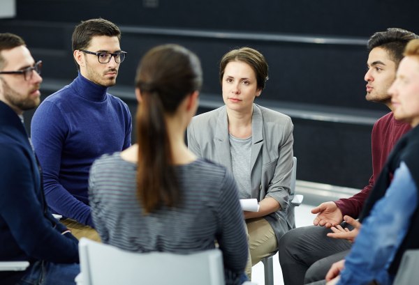 Small group seated in a circle discussion in a classroom or therapy setting.